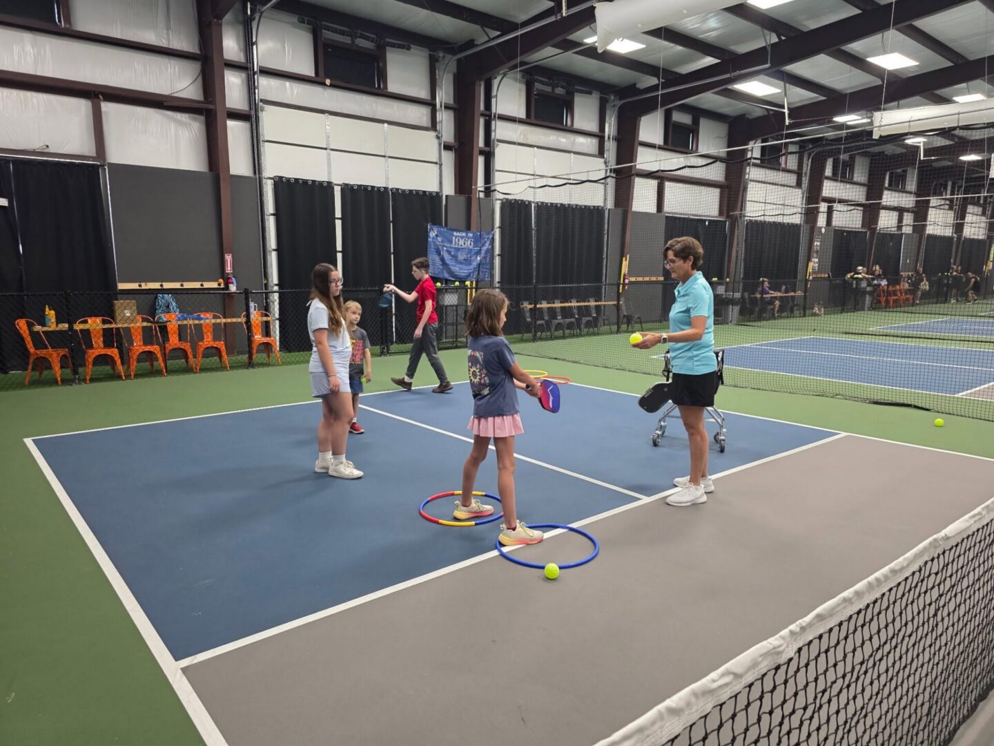 Coach leading young players through an on-court lesson at Indoor Pickleball Now